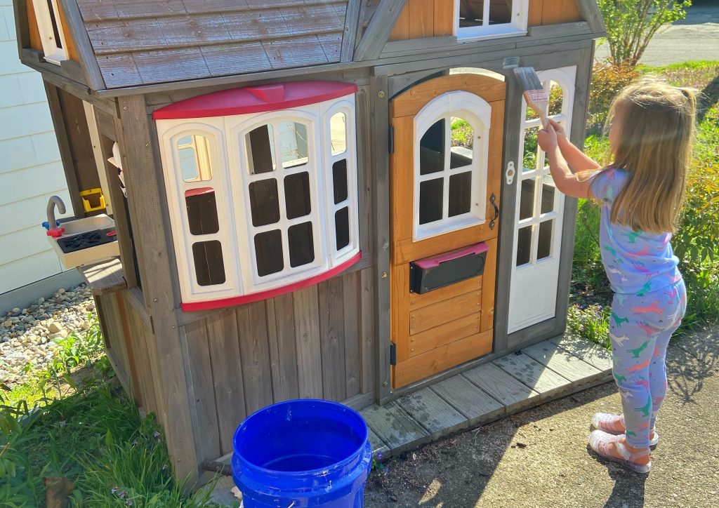 Warm weather activity - young girl painting play house with water