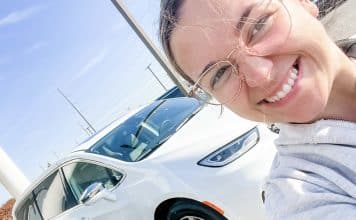 Woman in front of white hybrid minivan